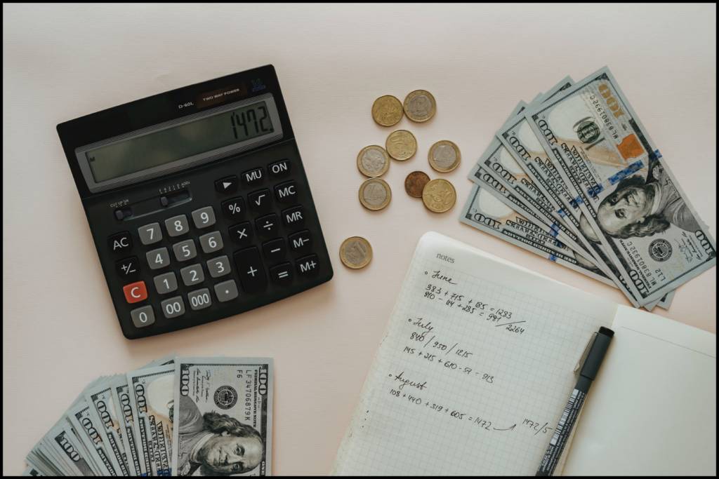 A calculator, notebook, and money on a table